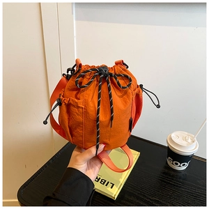 Detailed view of orange nylon bucket bag with polka dot drawstring and woven strap