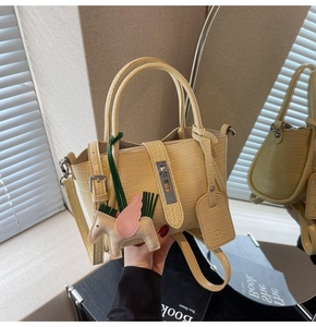 Detailed view of yellow crocodile embossed bucket bag with horse charm and silver lock