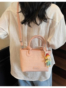 Pink woven crossbody bucket bag with a cute doll pendant and adjustable strap