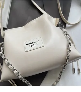 Close-up of cream leather bucket bag with mikaxiqi logo and chain strap detail