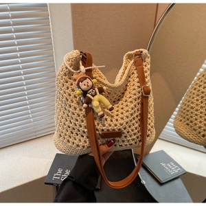 Detail of hand-woven cream tote bag with adjustable brown PU leather strap and charm