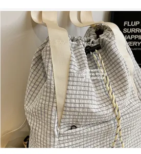 Detail of checkered bucket bag featuring black and white drawstring opening and canvas strap