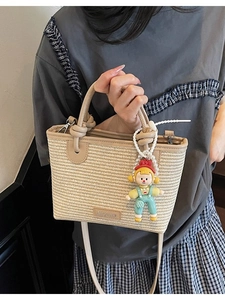 Handwoven straw bucket bag with brown leather trim and cute doll pendant for women
