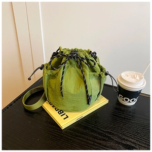 Close-up of grass green nylon bucket bag with drawstring closure and mesh side pocket