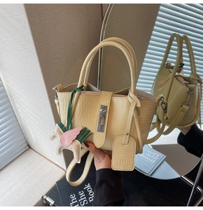 Detail of creamy yellow croc-embossed handbag with metal lock and cute horse charm