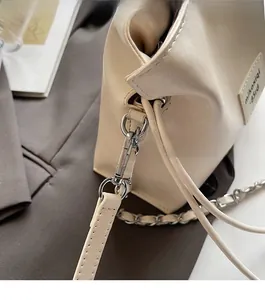 Detail of silver metal buckle and fine stitching on a beige leather shell bag