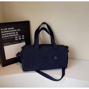 Detail of dark blue nylon travel bag with metal hex buckle and adjustable strap on a stand