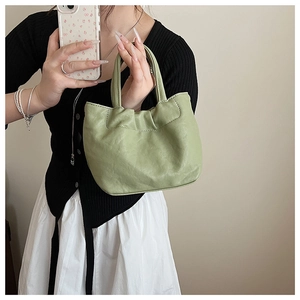 Detail of matcha green pleated bucket bag showing soft PU texture and handle craftsmanship