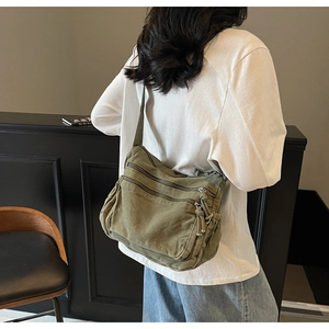 Detail view of large olive green canvas crossbody bag showing multiple zip compartments