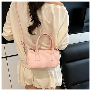 Pink pleated barrel crossbody bag shown on model with shoulder strap and top handles