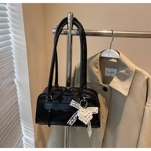 Vue détaillée d'un sac cabas noir brillant avec un nœud en dentelle et pendentif perle