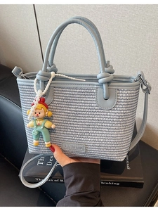 Blue and white woven straw bucket bag with leather handles and cute doll pendant accessory