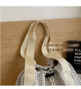 Detail showing checkered canvas bucket bag with drawstrings and woven beige handle straps