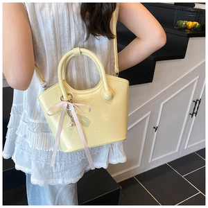 Détail du sac seau jaune crème avec nœud en ruban rose et breloque cœur perlé