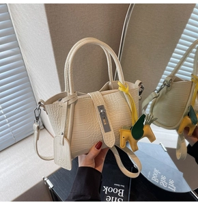 Close-up of off-white crocodile pattern handbag with silver clasp and yellow pony charm