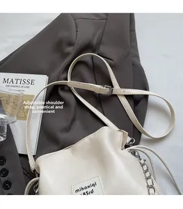 Close-up of cream leather bucket bag featuring adjustable strap and silver chain detail