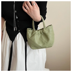 Detail of light green faux leather tote bag showing soft textured folds and handle straps