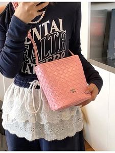 Pink woven leather bucket bag with top handle and crossbody strap for women