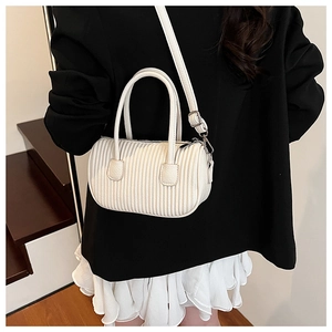 Detailed view of a white ruched cylinder bag with silver hardware on a model jacket