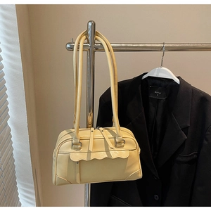 Detail of a creamy yellow retro shoulder bag with scalloped flap and dual zippers