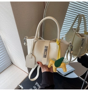 Detail view of beige crocodile embossed bucket bag with silver lock and pegasus charm