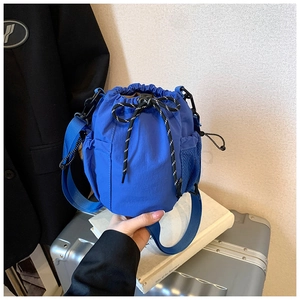 Blue nylon drawstring bucket bag with mesh side pocket and colorful decorative cords