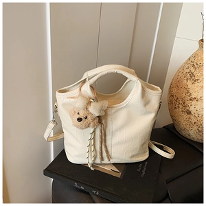 Detailed macro view of cream crocodile pattern handbag with cute plush bear charm