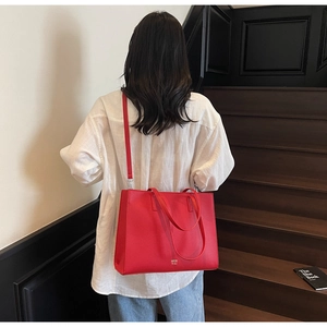 Red large capacity tote bag with lychee texture pattern shown in a lifestyle street setting