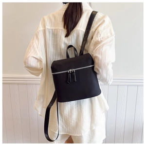 Close-up of minimalist black nylon backpack with durable silver metal zippers and top handle