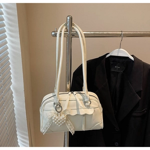 Détail d'un sac cabas en cuir mat crème avec bord festonné et breloque cœur perlé