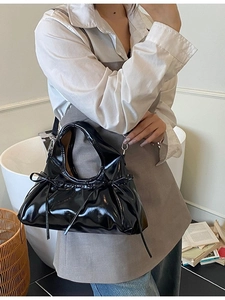 Elegant black patent leather handbag featuring bow accents and silver metal hardware details