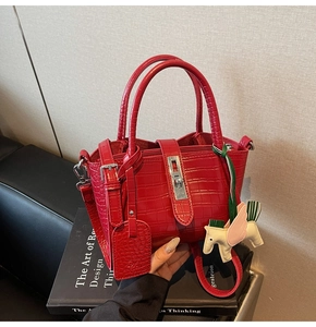 Detail of red crocodile texture handbag with silver twist lock and colorful pony charm