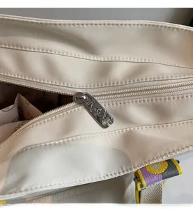 Close-up of smooth metal zipper and branded lining detail on beige tote bag