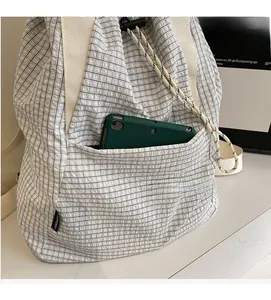 Close-up of black and white checkered drawstring bag showing a front pocket with a tablet