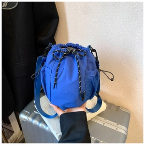 Detailed shot of a blue nylon bucket bag with drawstring closure and mesh side pocket