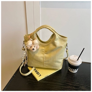 Detailed close-up of pale yellow crocodile texture handbag with plush bear charm