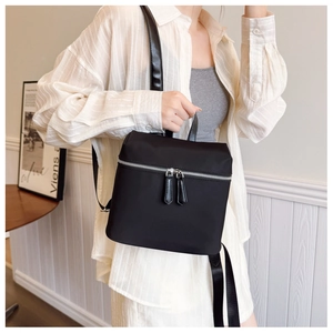 Detail of a black nylon mini backpack with silver double zippers and synthetic leather straps