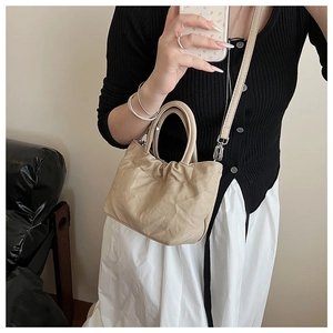 Detail of soft pleated apricot handbag featuring sturdy handles and silver metal hardware