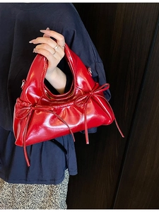 Fashionable red patent leather handbag with bow detail and sleek minimalist design