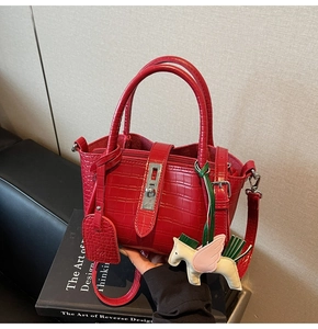 Detail of red crocodile texture handbag with silver twist lock and pegasus charm