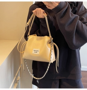 Detail of cream drawstring bucket bag with dual leather and metal chain straps