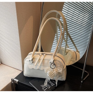 Detail of off-white leather Boston bag with wave stitching and pearl bow charm accessory