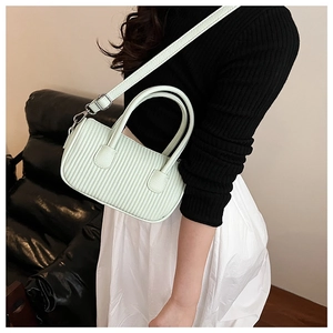 Detail of mint green pleated crossbody bag with circular handle and silver hardware