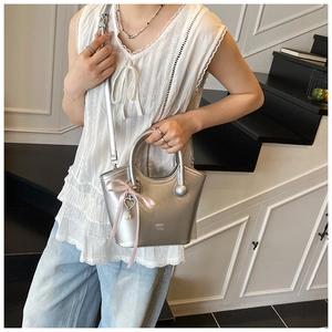 Close-up of silver bucket bag with GIHO 12AD embossing and a pink bow pearl charm