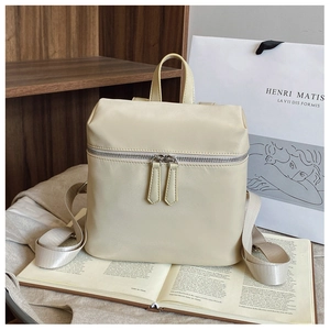 Close-up of cream minimalist nylon backpack featuring smooth texture and double front zippers