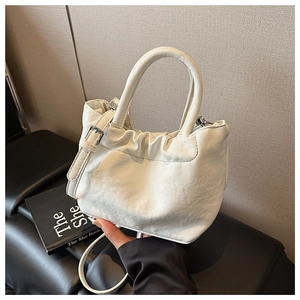 Close-up of white ruched bucket bag with integrated round handle and adjustable strap