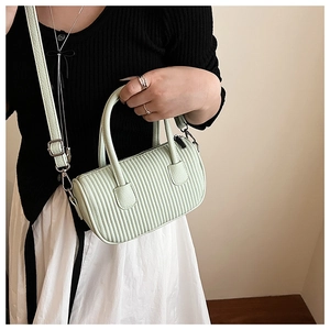 Close-up of mint green pleated cylinder bag with shoulder strap worn by a model