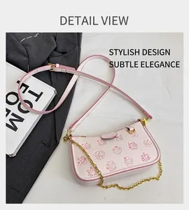 Détail d'un sac bandoulière rose en cuir grainé avec motif dessin animé et chaîne dorée