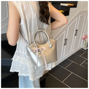 Silver metallic bucket bag with pink silk bow and heart pearl charm detail view
