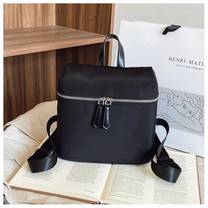 Close-up of black nylon backpack on a wooden bookshelf showing metal zipper details